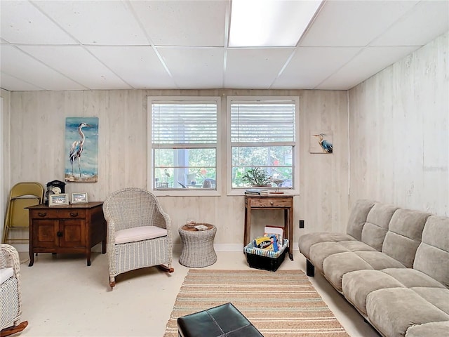 living room with a drop ceiling and concrete floors