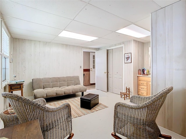 living room with a paneled ceiling and concrete floors