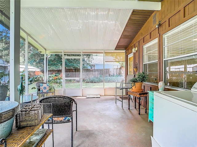 sunroom / solarium with washer / clothes dryer, vaulted ceiling, and a healthy amount of sunlight