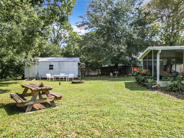 view of yard featuring a sunroom and an outdoor fire pit