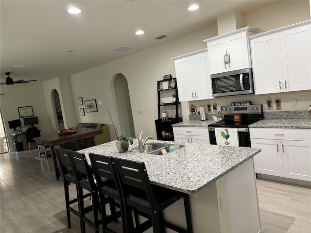 kitchen with an island with sink, sink, stainless steel appliances, and white cabinets