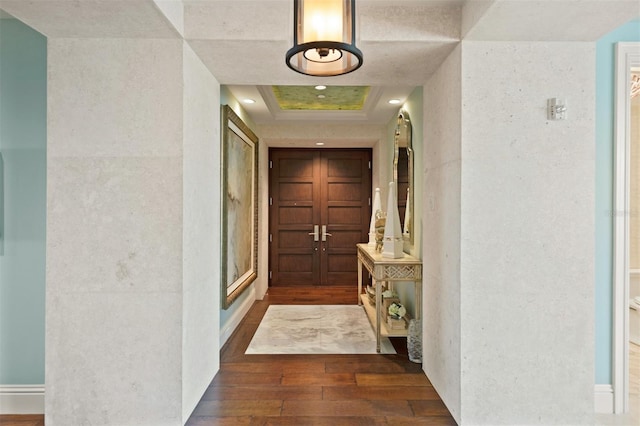 hall with a tray ceiling, dark wood finished floors, and recessed lighting