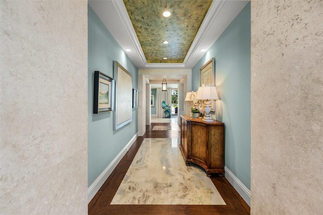 corridor featuring ornamental molding, a tray ceiling, and dark hardwood / wood-style flooring