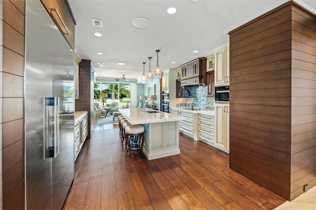 kitchen with pendant lighting, a kitchen breakfast bar, appliances with stainless steel finishes, dark hardwood / wood-style flooring, and a spacious island