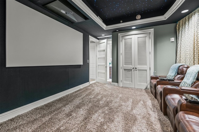 cinema featuring a raised ceiling, carpet flooring, and ornamental molding