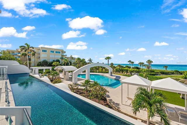 view of pool featuring a water view, a water slide, and a patio area