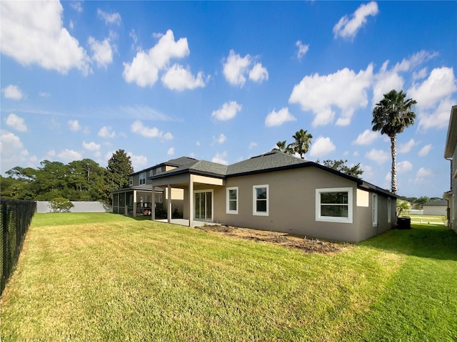 rear view of property with a yard, a sunroom, and central AC unit