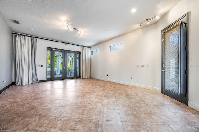 tiled spare room with french doors, a textured ceiling, and track lighting