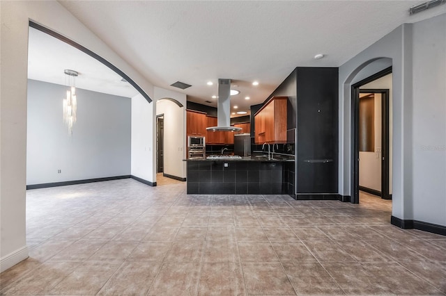 kitchen with appliances with stainless steel finishes, island exhaust hood, sink, and a textured ceiling