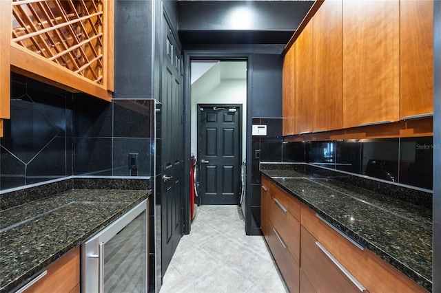 kitchen featuring beverage cooler, dark stone counters, and backsplash