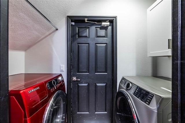 clothes washing area with a textured ceiling, separate washer and dryer, and cabinets