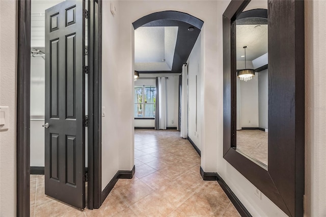 corridor featuring a textured ceiling and light tile patterned flooring