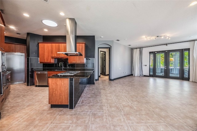 kitchen featuring appliances with stainless steel finishes, open floor plan, a sink, a kitchen island, and island range hood