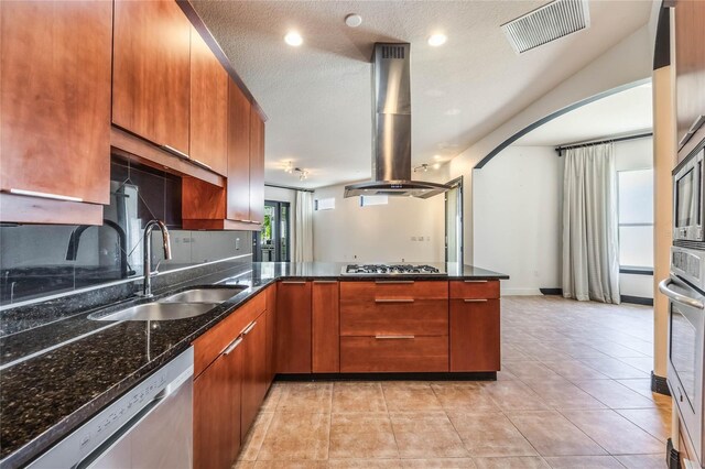 kitchen featuring visible vents, dark stone countertops, island exhaust hood, stainless steel appliances, and a sink