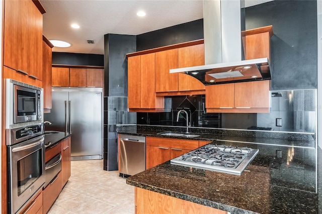 kitchen with tasteful backsplash, a sink, dark stone countertops, island range hood, and built in appliances