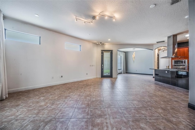 unfurnished living room with arched walkways, visible vents, a textured ceiling, tile patterned flooring, and baseboards