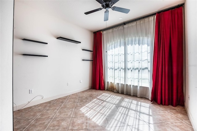 empty room featuring light tile patterned flooring, ceiling fan, and baseboards