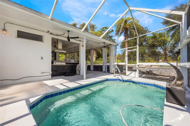 outdoor pool with ceiling fan, a patio, exterior kitchen, and a lanai