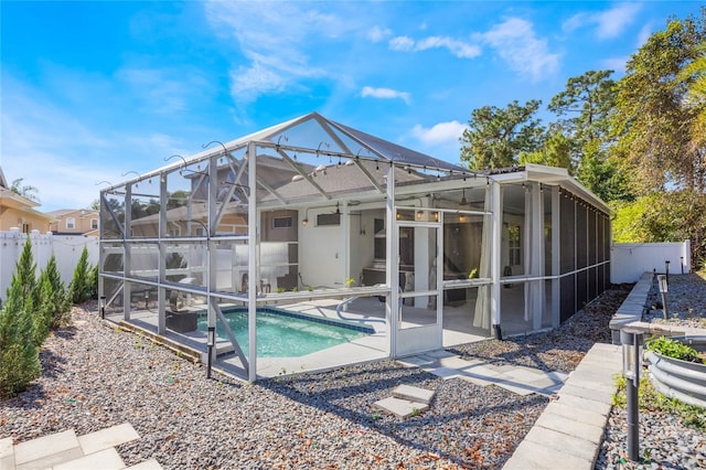 back of property with a fenced in pool, fence private yard, glass enclosure, and a patio