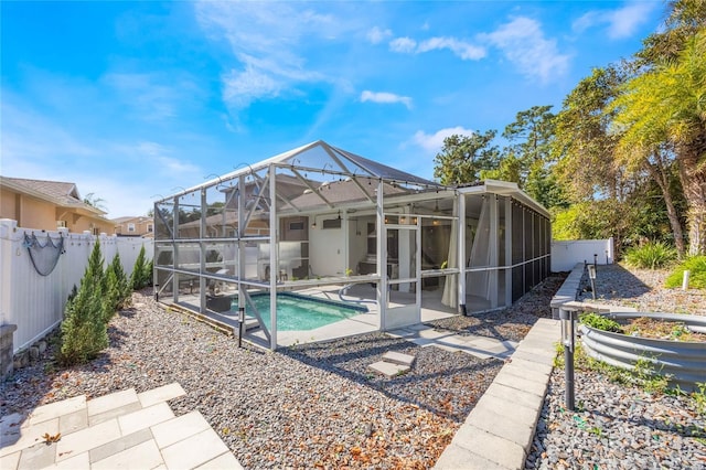 rear view of property with glass enclosure, a fenced backyard, a fenced in pool, and a patio