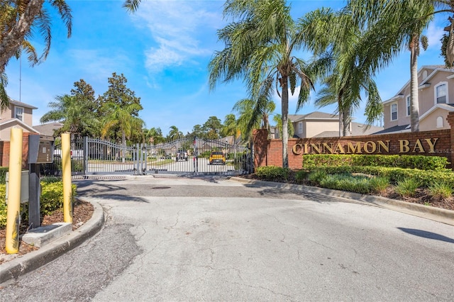 view of road featuring a gate, a residential view, a gated entry, and curbs