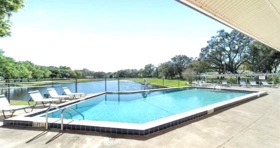 view of pool featuring a patio area and a water view