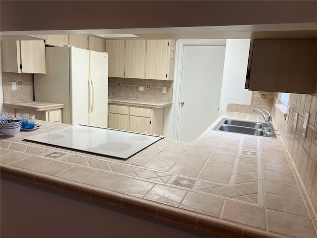 kitchen featuring tasteful backsplash, tile countertops, sink, and white fridge