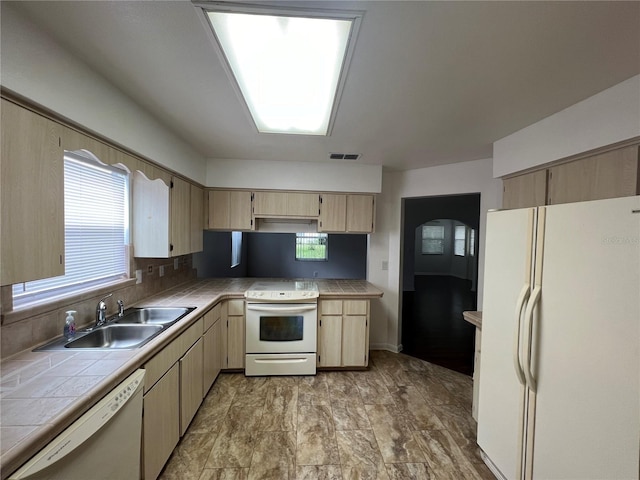 kitchen featuring light brown cabinetry, sink, white appliances, and tile countertops