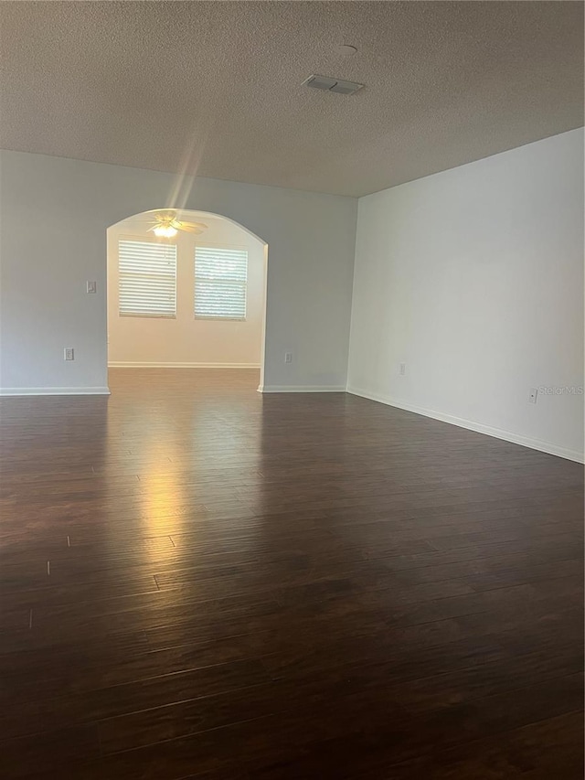 empty room featuring ceiling fan, dark hardwood / wood-style flooring, and a textured ceiling