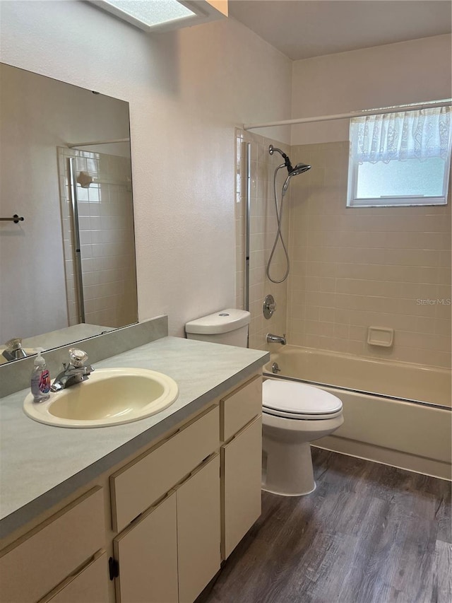 full bathroom featuring toilet, vanity, wood-type flooring, and tiled shower / bath