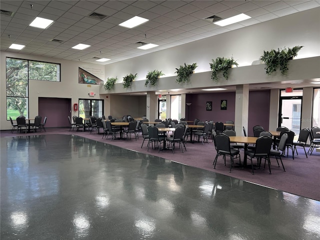 interior space with plenty of natural light, a drop ceiling, and a high ceiling