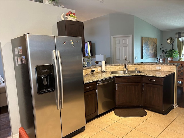 kitchen with appliances with stainless steel finishes, light stone counters, backsplash, kitchen peninsula, and sink