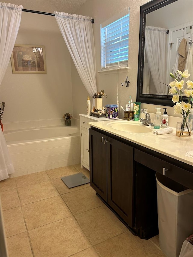 bathroom with tiled tub, vanity, and tile patterned flooring