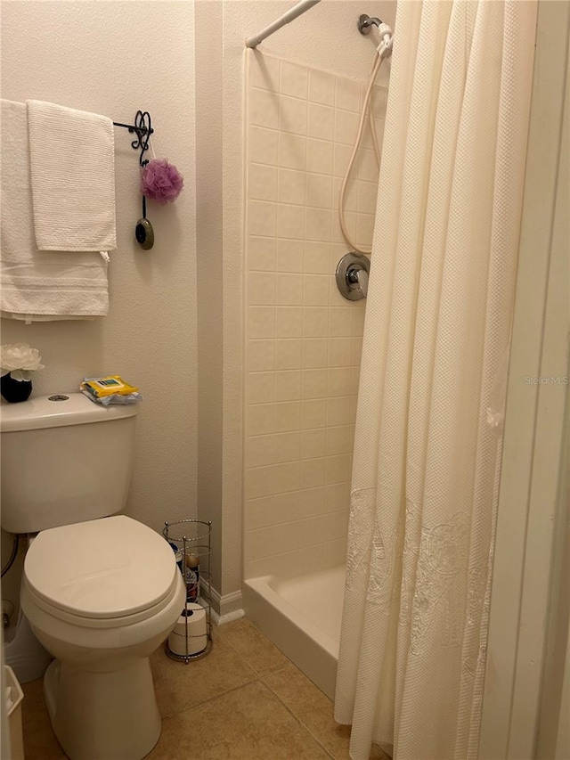 bathroom with a shower with curtain, tile patterned floors, and toilet