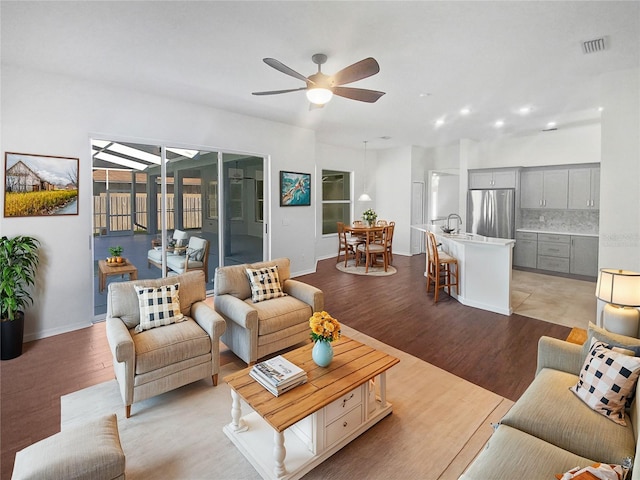 living room with ceiling fan, light hardwood / wood-style flooring, and sink