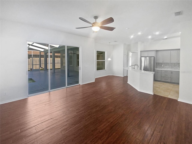 unfurnished living room featuring light hardwood / wood-style flooring, ceiling fan, and sink