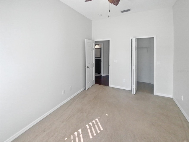 unfurnished bedroom with ceiling fan, light colored carpet, a closet, and a spacious closet