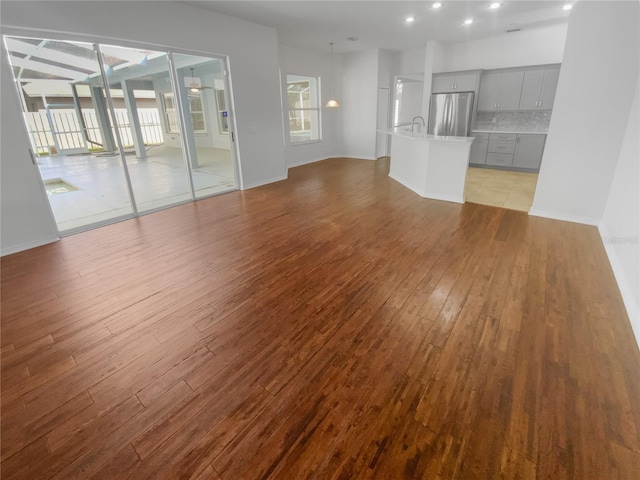 unfurnished living room featuring light wood finished floors, recessed lighting, and baseboards