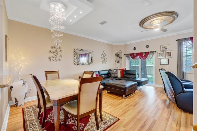 dining room featuring hardwood / wood-style flooring, ceiling fan with notable chandelier, crown molding, and a healthy amount of sunlight