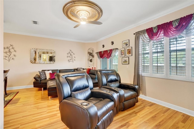 home theater room featuring ceiling fan, ornamental molding, and light hardwood / wood-style floors