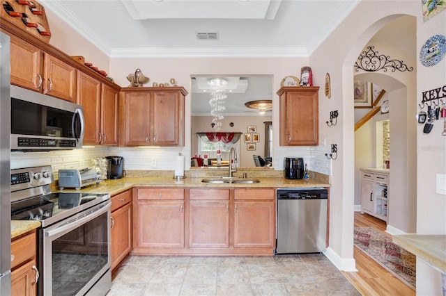 kitchen with sink, tasteful backsplash, appliances with stainless steel finishes, crown molding, and light hardwood / wood-style floors