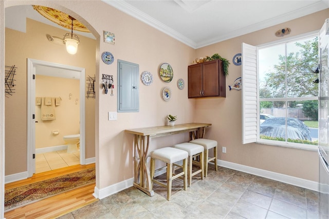 dining space featuring electric panel, light wood-type flooring, and crown molding