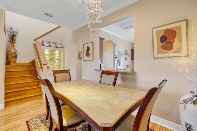 dining room with a notable chandelier, light hardwood / wood-style flooring, and ornamental molding