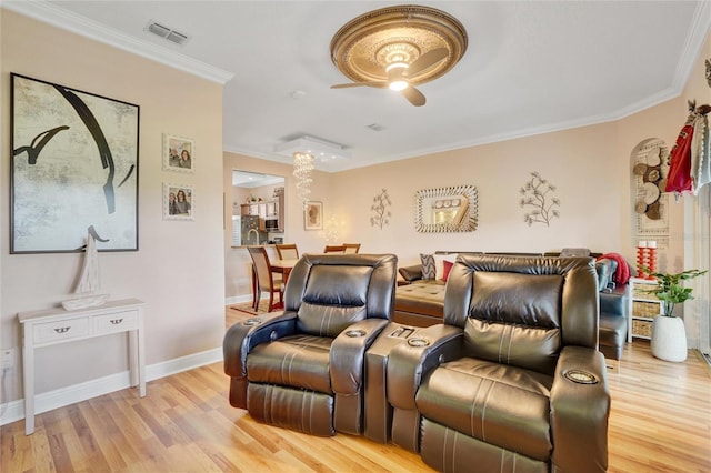 cinema room with crown molding, ceiling fan, and light hardwood / wood-style flooring