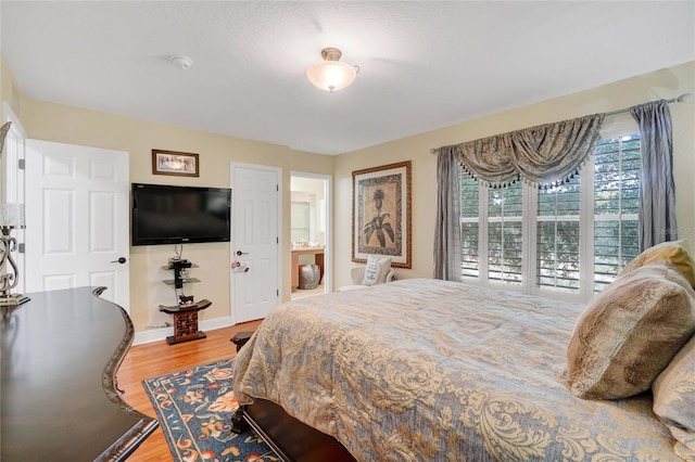 bedroom featuring hardwood / wood-style flooring and connected bathroom