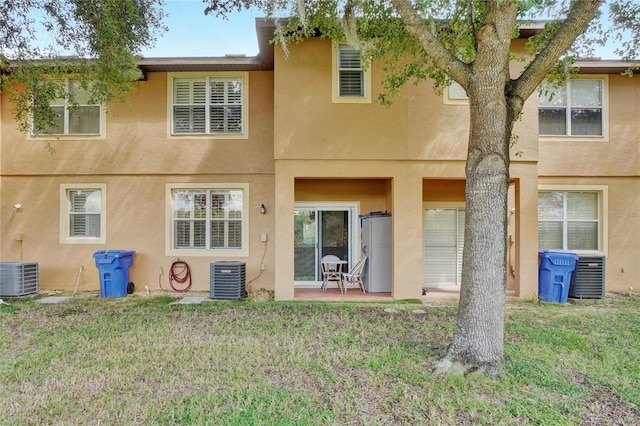 rear view of property with a patio, cooling unit, and a lawn