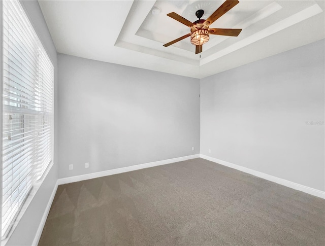 spare room with ceiling fan, a raised ceiling, and carpet