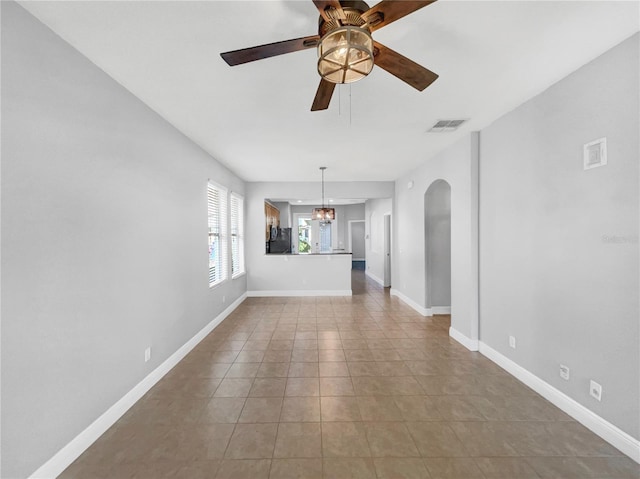 unfurnished living room featuring ceiling fan with notable chandelier and light tile patterned floors