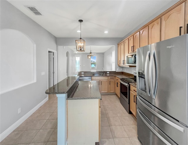 kitchen with dark stone counters, sink, kitchen peninsula, appliances with stainless steel finishes, and decorative light fixtures