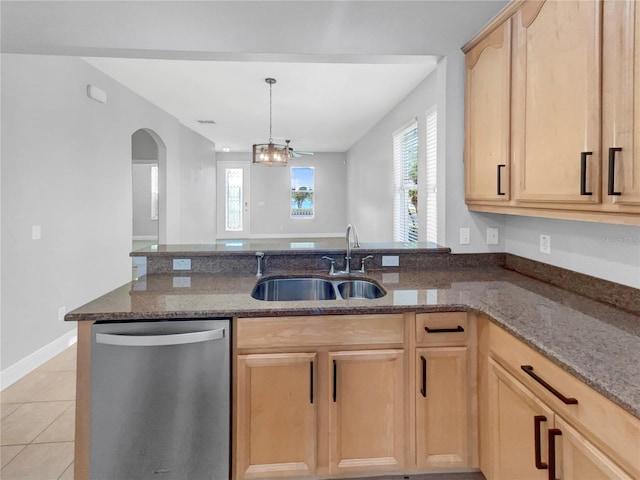 kitchen featuring dark stone countertops, dishwasher, light brown cabinetry, and sink